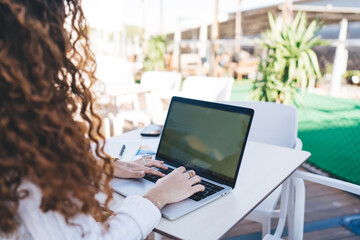 Crop young woman browsing laptop in outdoor cafe