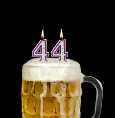 number 44 candles in beer mug for birthday celebration isolated on black 