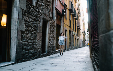 Fototapeta na wymiar Young female walking on narrow street and looking at wristwatch