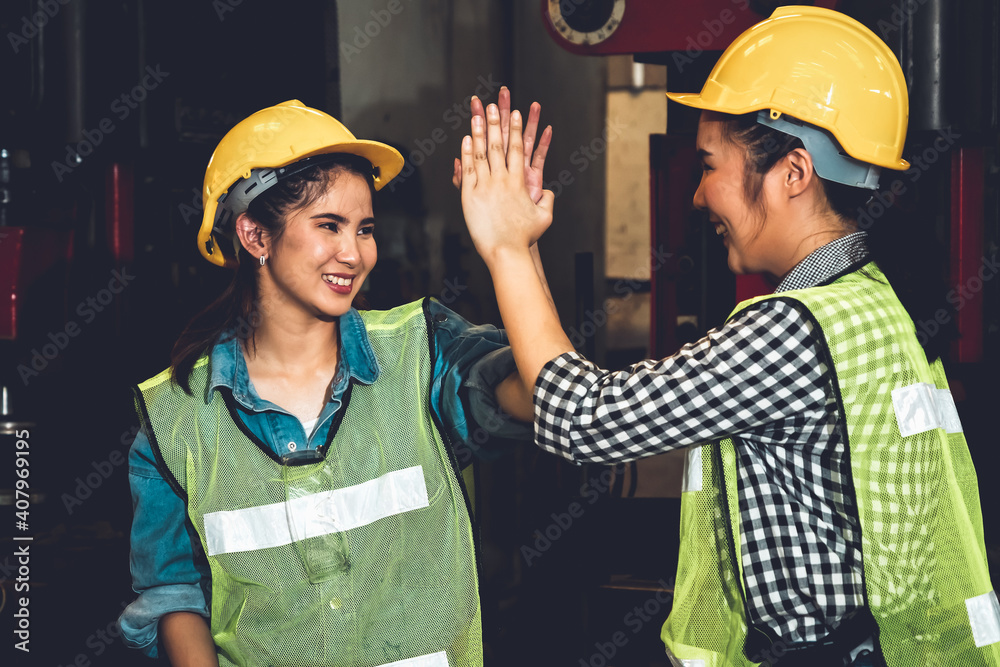 Wall mural Two factory job worker celebrate success together in the manufacturing workshop or warehouse . Industry work achievement concept .