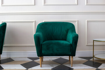 Bottle green soft vintage armchair. Rifle-green velvet armchair next to white wall