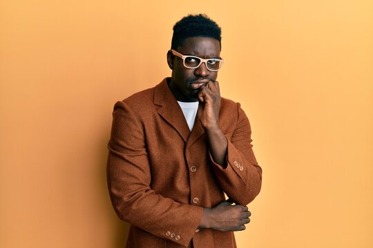 Handsome black man wearing elegant clothes and glasses thinking concentrated about doubt with finger on chin and looking up wondering