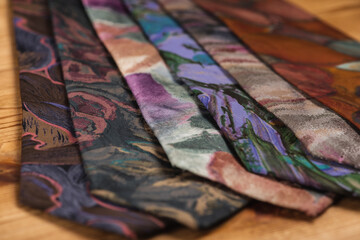 close-up view, many multi-colored folded, twisted ties, sloping horizon. Textured background of classic fabrics