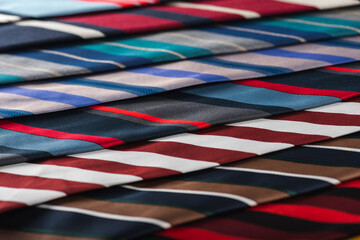 Fototapeta na wymiar close-up view, many colorful folded ties, sloping horizon. Textured background of classic fabrics