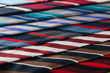 close-up view, many colorful folded ties, sloping horizon. Textured background of classic fabrics