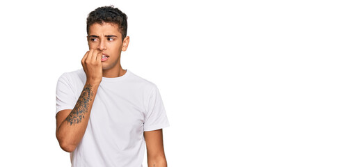 Young handsome african american man wearing casual white tshirt looking stressed and nervous with hands on mouth biting nails. anxiety problem.