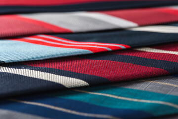 close-up view, many colorful folded ties, sloping horizon. Textured background of classic fabrics
