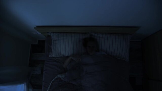 Time lapse of man rolling over in bed trying to sleep at night, top view, double exposure technique.