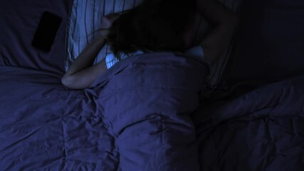 Time lapse of woman rolling over in bed trying to sleep at night, top view, double exposure technique. 