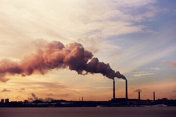 Power plant silhouette in the winter at sunset. View of pipes with smoke after burning coal.