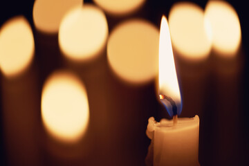 Close-up of a burning home candle against a bokeh background of a group of burning candles