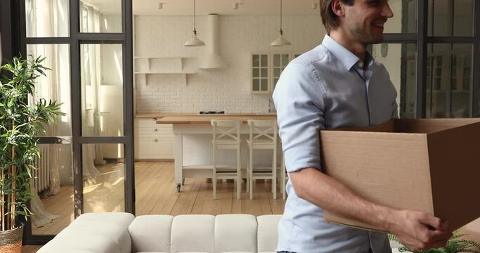 Happy young couple bringing carton boxes with packed personal staff into new apartment, feeling excited of changing accommodation, moving into first own house, real estate relocation concept.