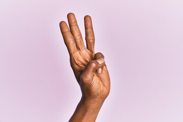 Arm and hand of black middle age woman over pink isolated background counting number 3 showing...