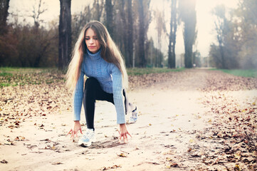 Young caucasian woman in blue sweater running in the autumn forest