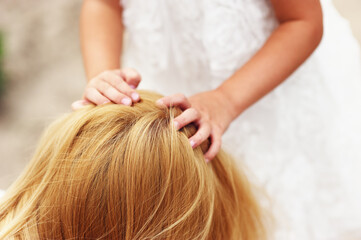 Obraz premium Young blonde mother in dress playing with little kid blonde daughter in the park.