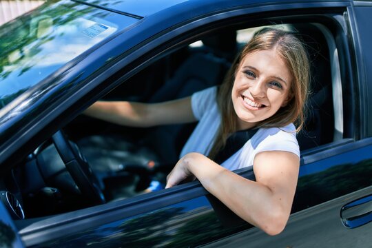 Young beautiful blonde woman smiling happy driving car