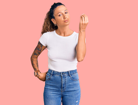 Young hispanic woman with tattoo wearing casual white tshirt doing italian gesture with hand and fingers confident expression