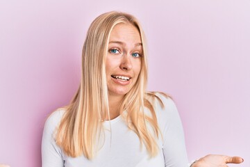 Young blonde girl wearing casual clothes clueless and confused expression with arms and hands...