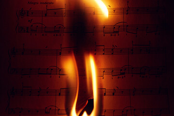 Close-up of a flame on a sheet of music.