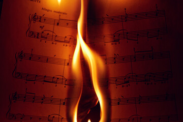 Close-up of a flame on a sheet of music.