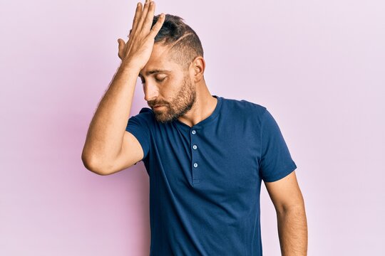 Handsome man with beard wearing casual clothes surprised with hand on head for mistake, remember error. forgot, bad memory concept.