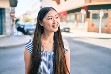 Young chinese woman smiling happy walking at street of city.