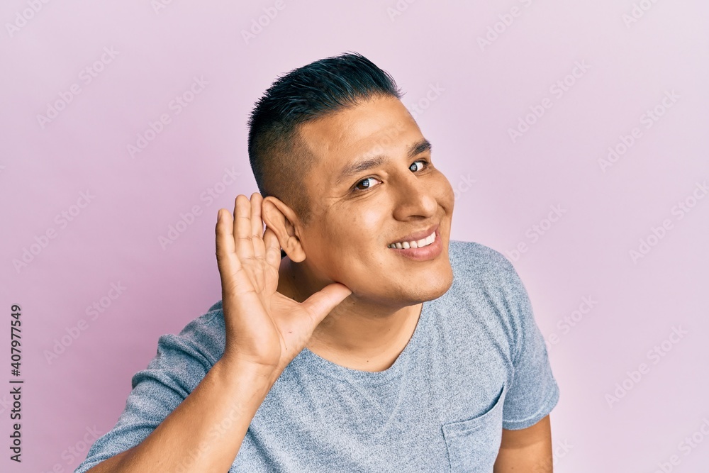 Sticker young latin man wearing casual clothes smiling with hand over ear listening and hearing to rumor or 