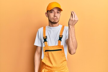 Hispanic young man wearing handyman uniform doing italian gesture with hand and fingers confident expression