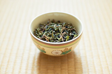 Closeup of a cup with leaves of Chinese tea on the table indoors.