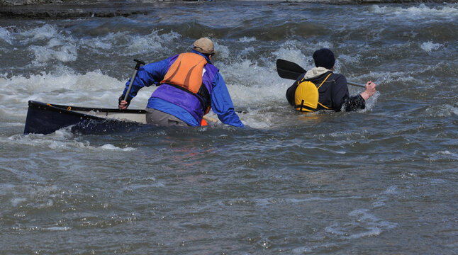 Two People In Sinking Canoe In Rapids