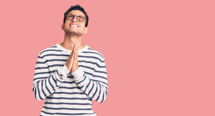 Hispanic handsome young man wearing casual clothes and glasses begging and praying with hands...