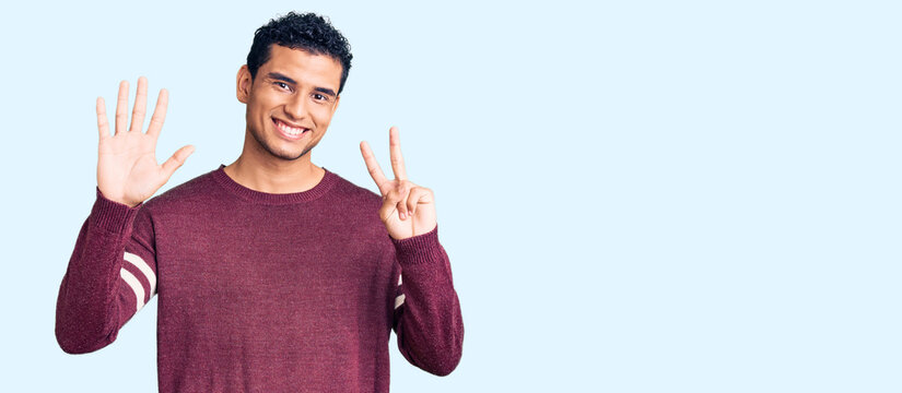 Hispanic handsome young man wearing casual clothes showing and pointing up with fingers number seven while smiling confident and happy.