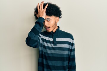 Young african american man with afro hair wearing casual clothes surprised with hand on head for mistake, remember error. forgot, bad memory concept.