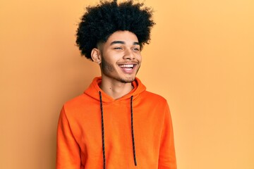 Fototapeta na wymiar Young african american man with afro hair wearing casual sweatshirt looking to side, relax profile pose with natural face and confident smile.