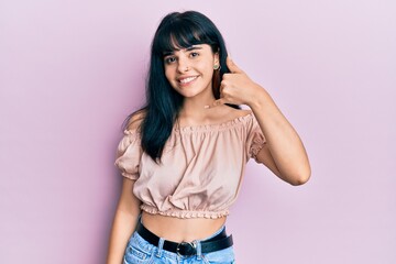 Young hispanic girl wearing casual clothes smiling doing phone gesture with hand and fingers like talking on the telephone. communicating concepts.