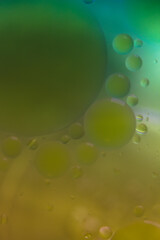 Blurred soft focus of oil spheres in water with color transition from green to yellow tones for colorful background