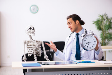 Young male doctor and skeleton patient in time management concep