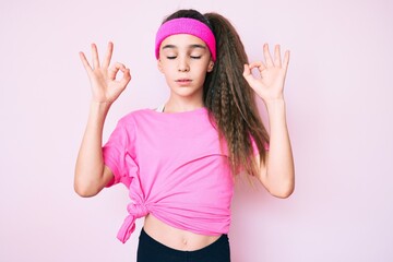 Obraz na płótnie Canvas Cute hispanic child girl wearing sportswear relax and smiling with eyes closed doing meditation gesture with fingers. yoga concept.