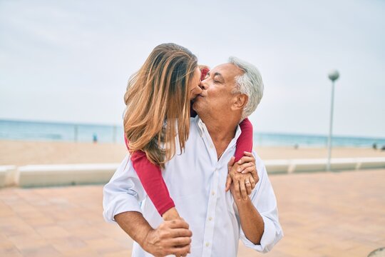 Middle age hispanic couple kissing and hugging walking at street.