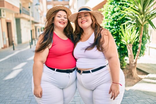 Two plus size overweight sisters twins women hugging together outdoors