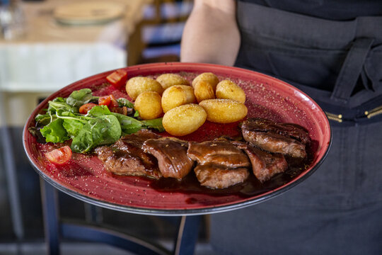 Waiter Serving A Delicious Steak With Potatoes