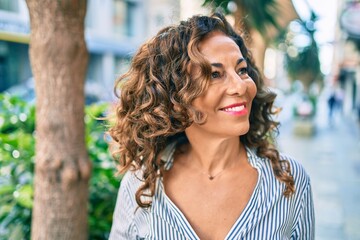 Middle age hispanic woman smiling happy walking at the city.