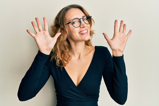 Young caucasian woman wearing business shirt and glasses showing and pointing up with fingers number ten while smiling confident and happy.
