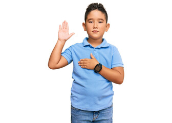 Little boy hispanic kid wearing casual clothes swearing with hand on chest and open palm, making a...