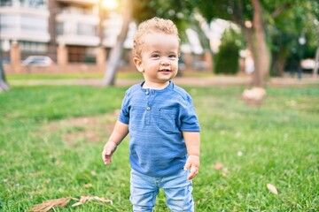 Cute and happy little boy having fun at the park on a sunny day. Beautiful blonde hair male toddler playing outdoors