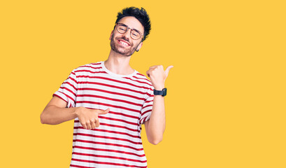 Young hispanic man wearing casual clothes pointing to the back behind with hand and thumbs up, smiling confident