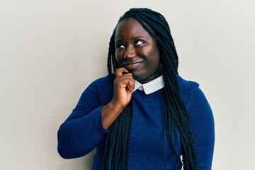 Young black woman with braids wearing casual clothes thinking concentrated about doubt with finger on chin and looking up wondering