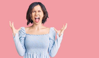 Young beautiful girl wearing casual clothes crazy and mad shouting and yelling with aggressive expression and arms raised. frustration concept.