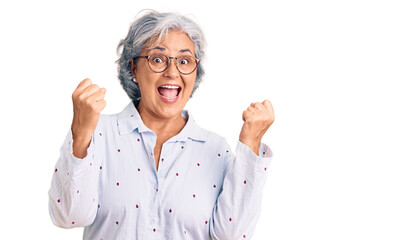 Senior woman with gray hair wearing casual business clothes and glasses screaming proud, celebrating victory and success very excited with raised arms