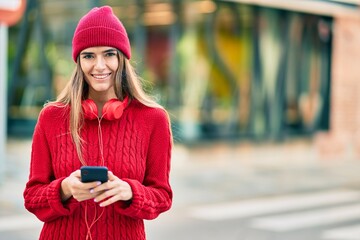 Young hispanic woman using smartphone and headphones at the city.